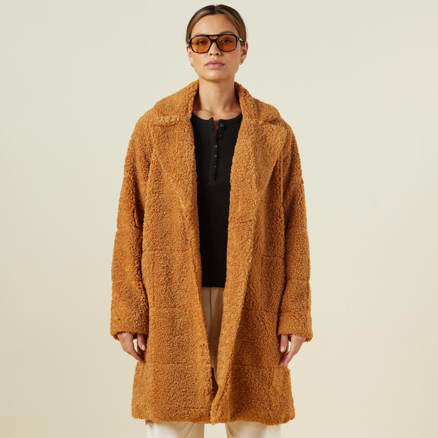 Front view of model wearing the teddy coat in camel.