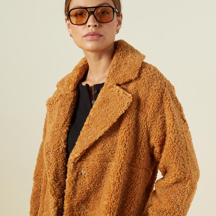 Close up view of model wearing the teddy coat in camel.