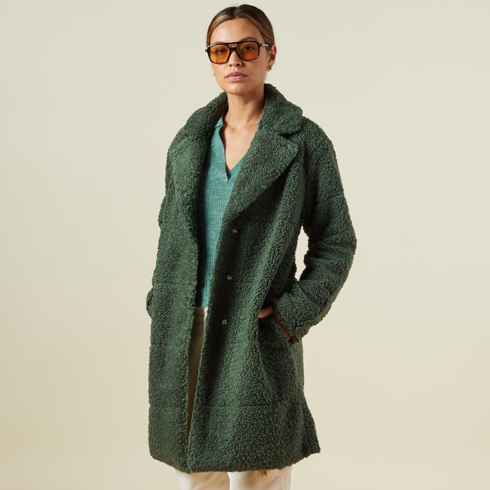Side view of model wearing the teddy coat in forest.