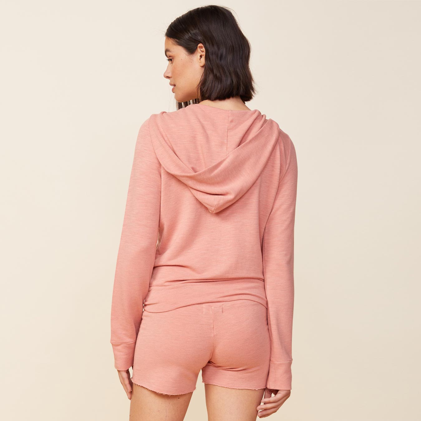 Back view of model wearing the supersoft zip up hoody in faded coral.