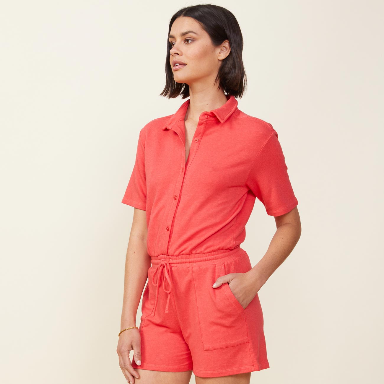 Side view of model wearing the supersoft romper in fire coral.