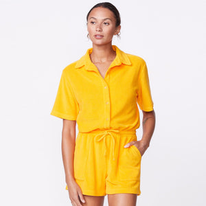 Front view of model wearing the terry cloth romper in marigold.