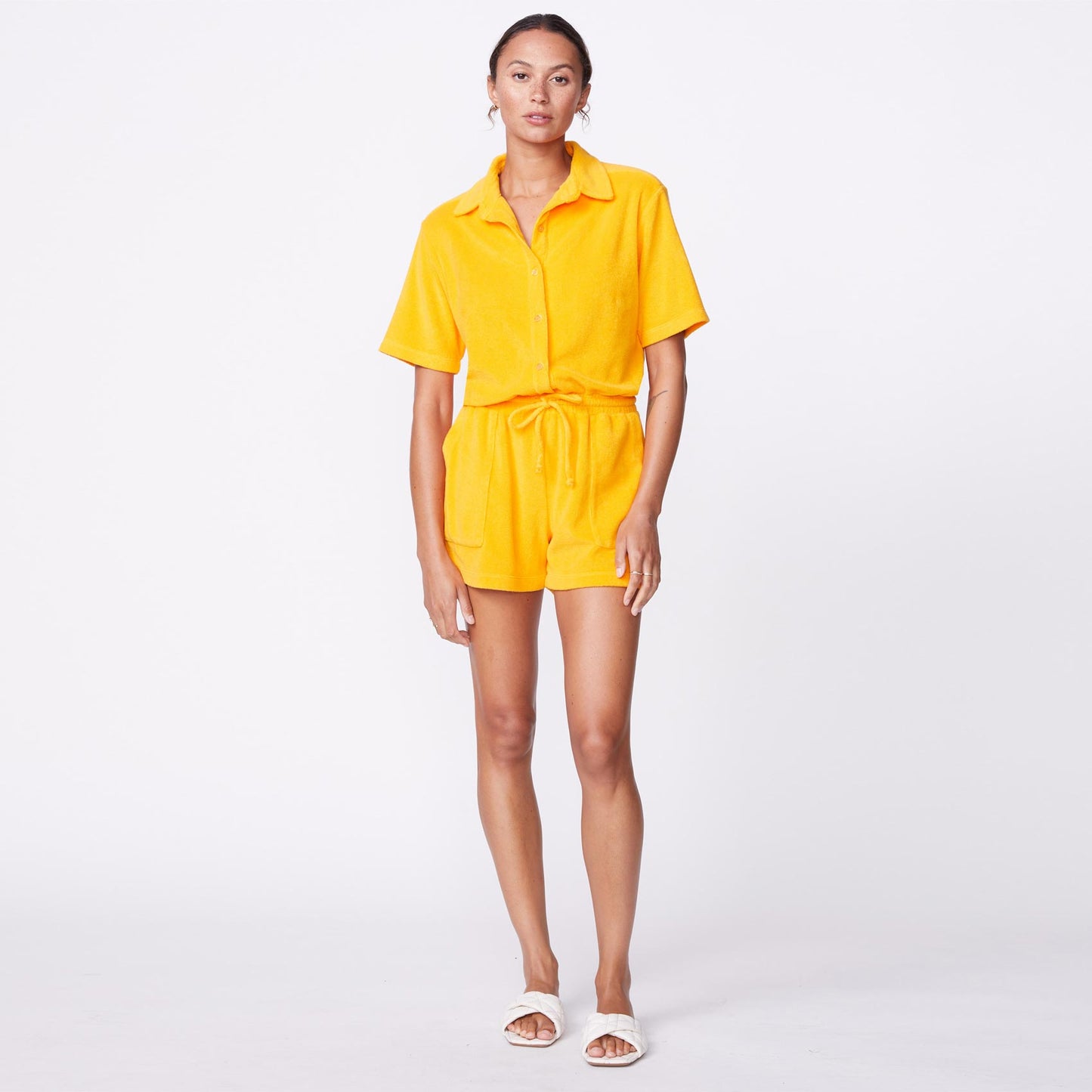 Front view of model wearing the terry cloth romper in marigold.