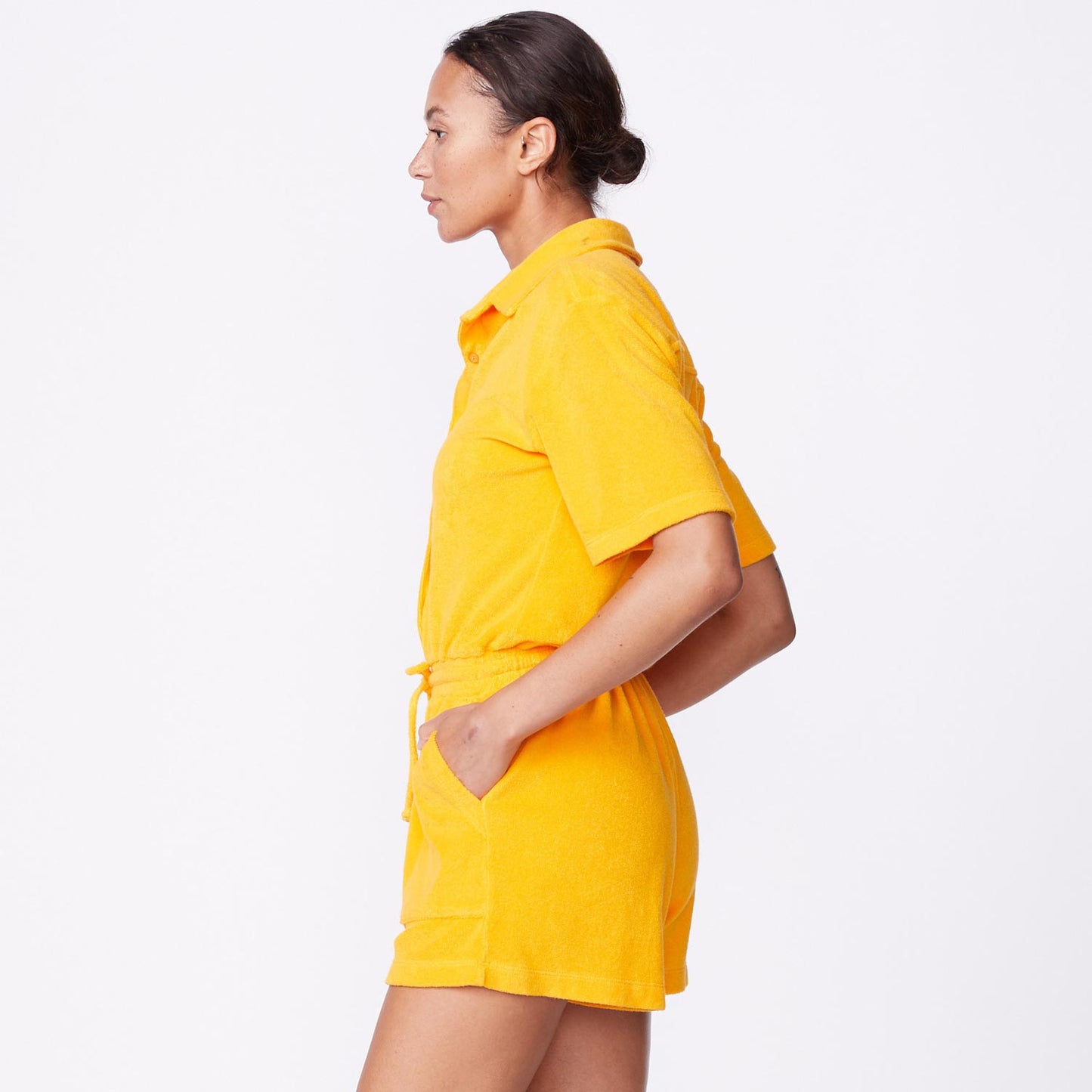Side view of model wearing the terry cloth romper in marigold.