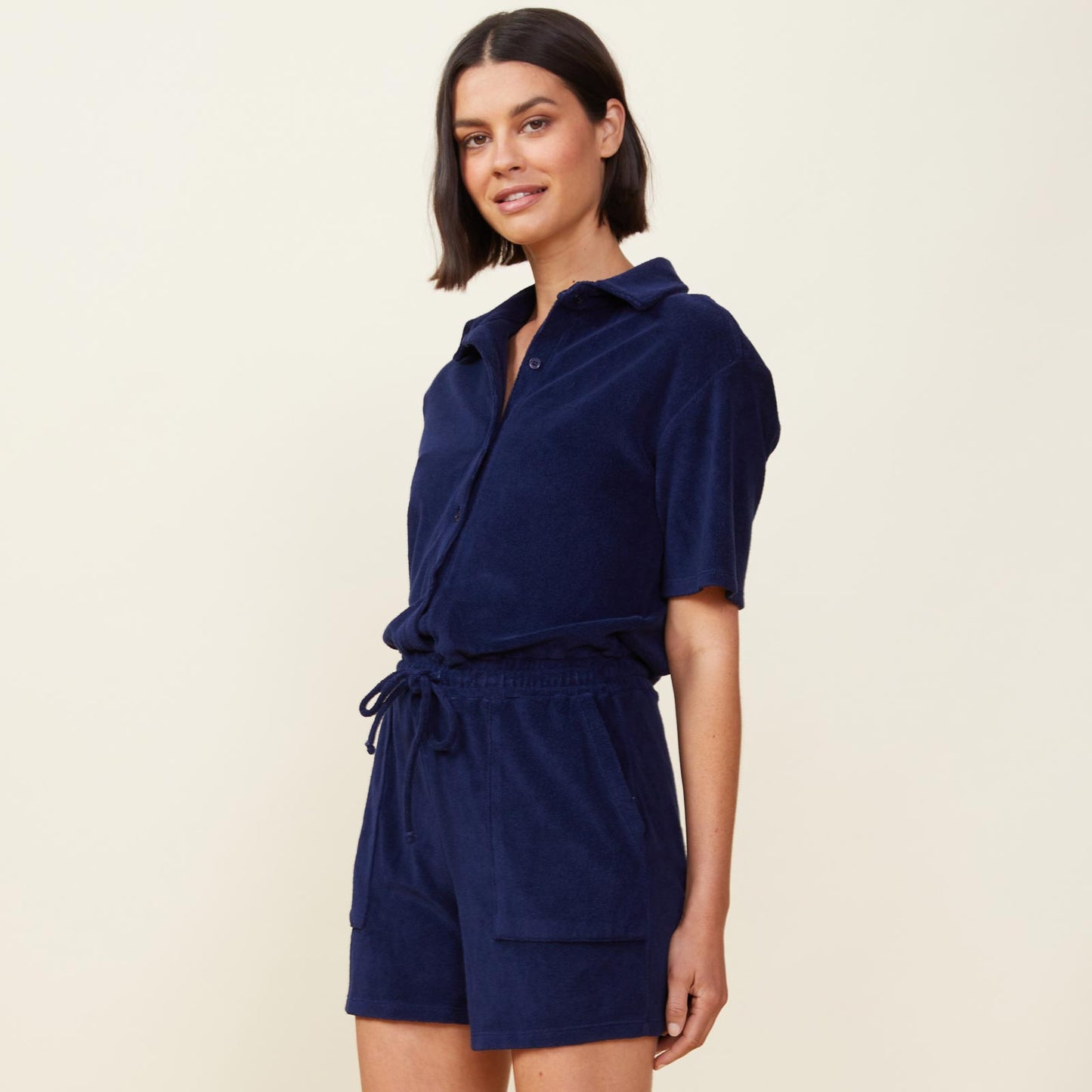 Side view of model wearing the terry cloth romper in navy.