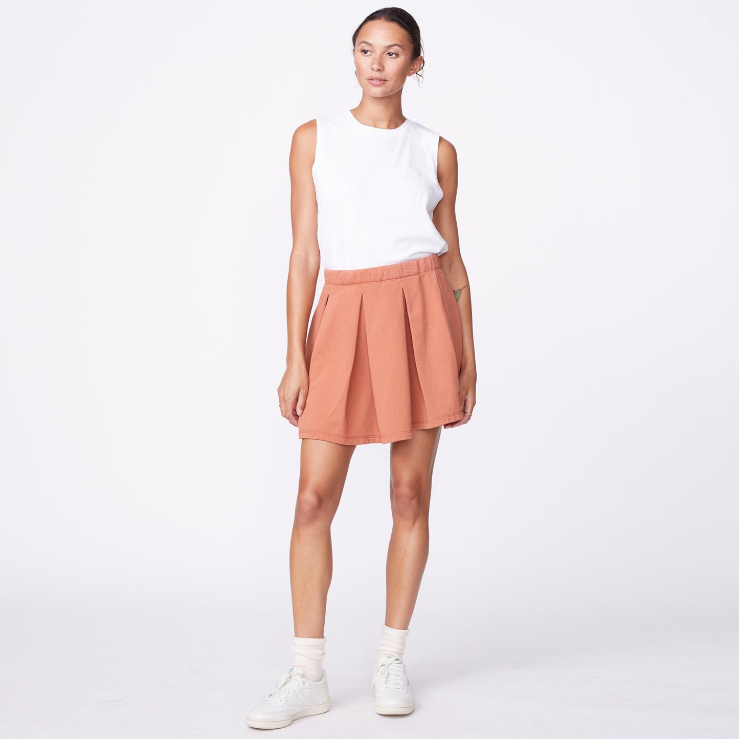 Front view of model wearing the 90's classic tennis skirt in faded rust.