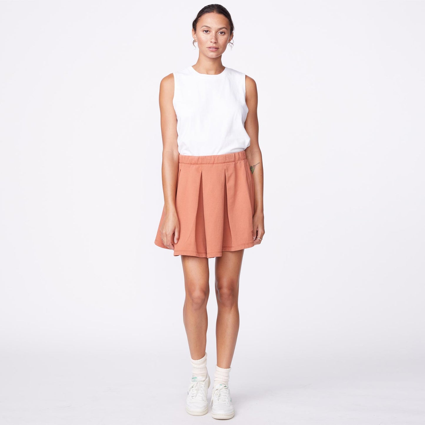 Front view of model wearing the 90's classic tennis skirt in faded rust.