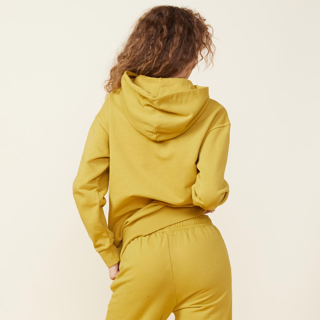 Back view of model wearing the 90's classic hoody in golden olive.