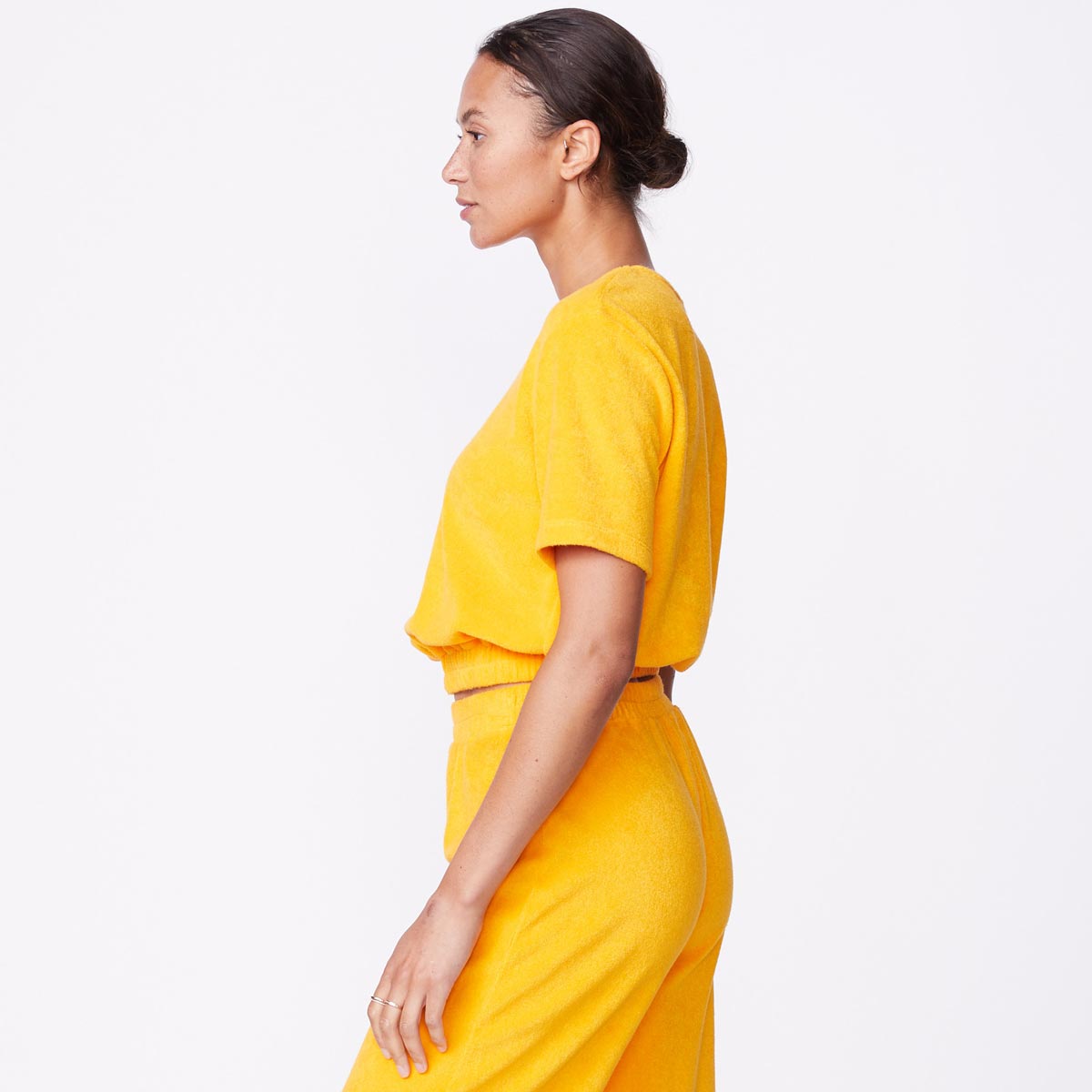 Side view of model wearing the terry cloth tee in marigold.