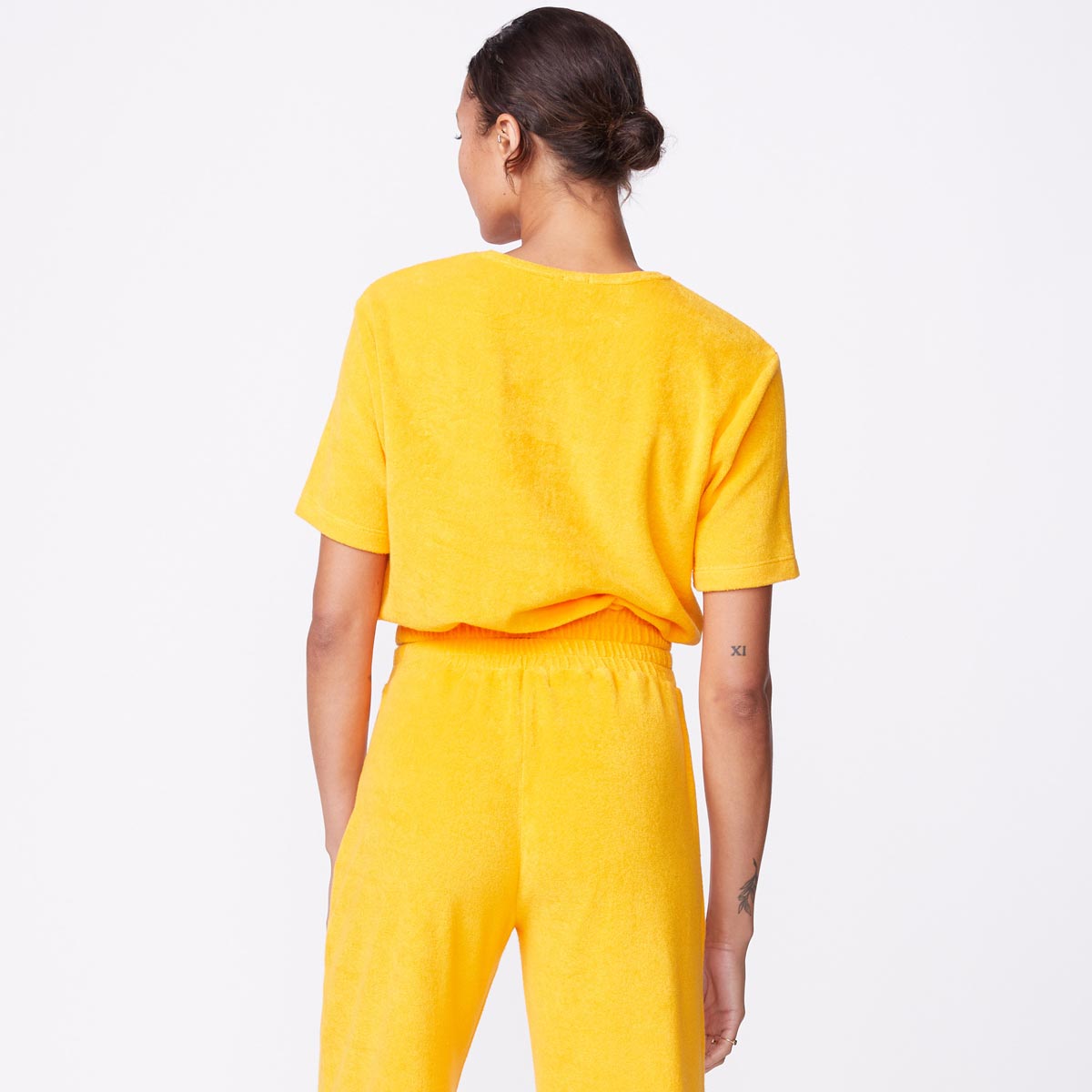 Back view of model wearing the terry cloth tee in marigold.