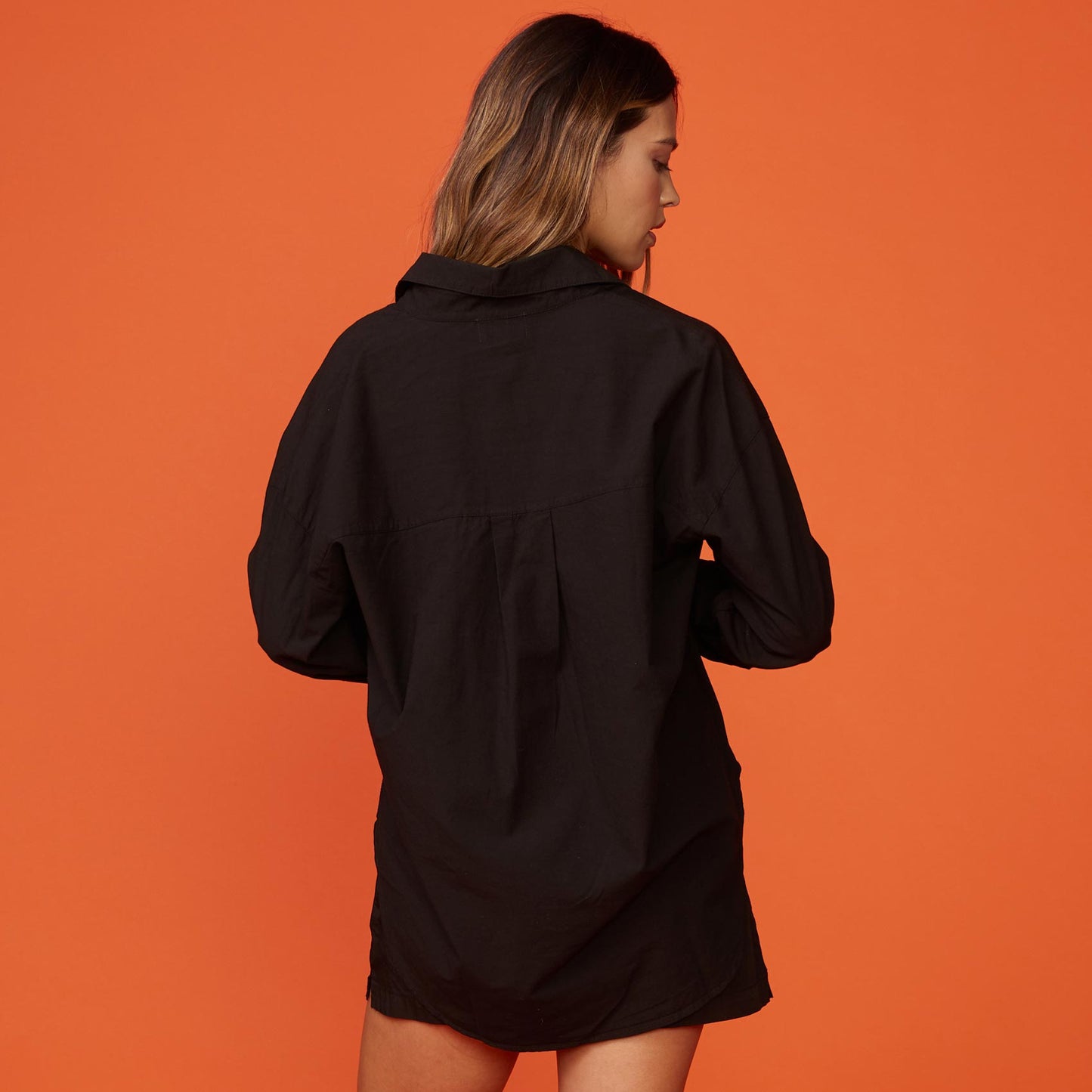 Back view of model wearing the poplin shirt in black.