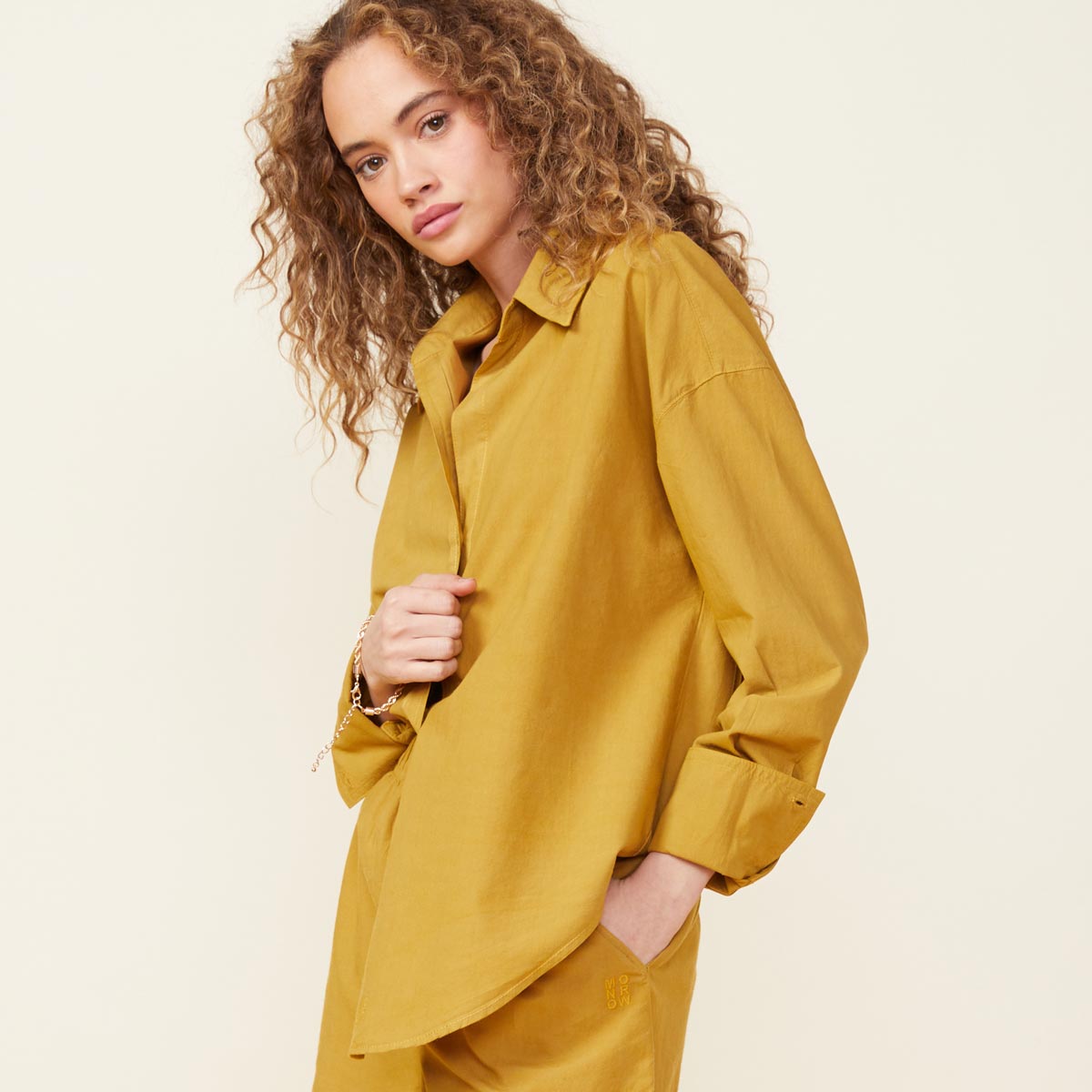 Front view of model wearing the poplin shirt in golden olive.
