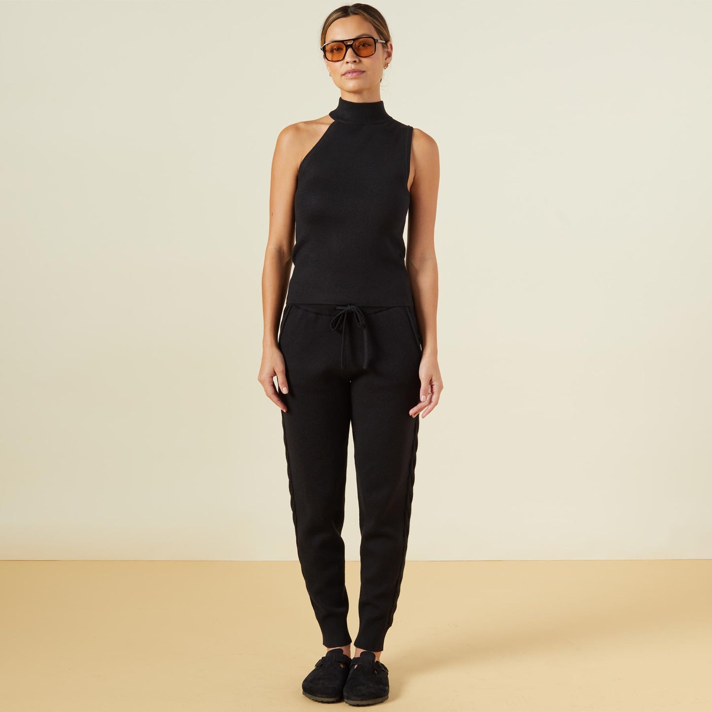 Front view of model wearing the supersoft sweater knit asymmetric mock neck tank in black.