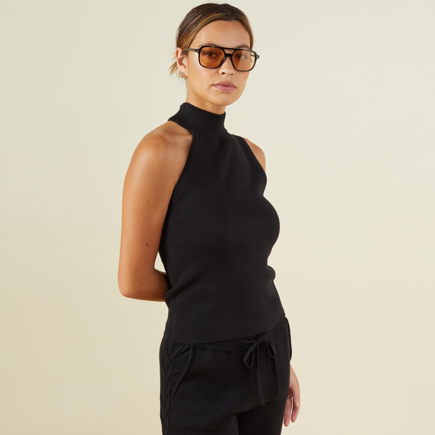 Side view of model wearing the supersoft sweater knit asymmetric mock neck tank in black.
