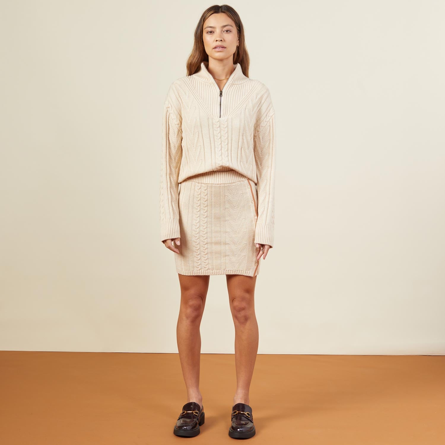 Front view of model wearing the merino cable knit half zip in off white.