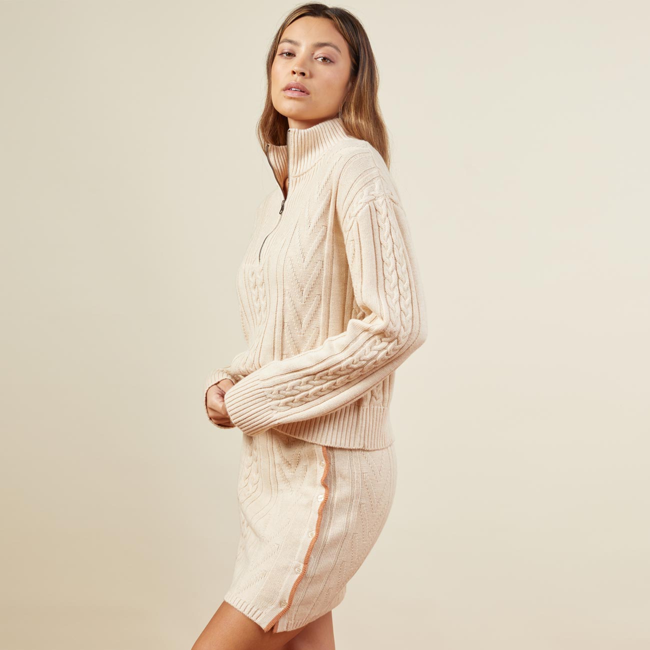 Side view of model wearing the merino cable knit half zip in off white.