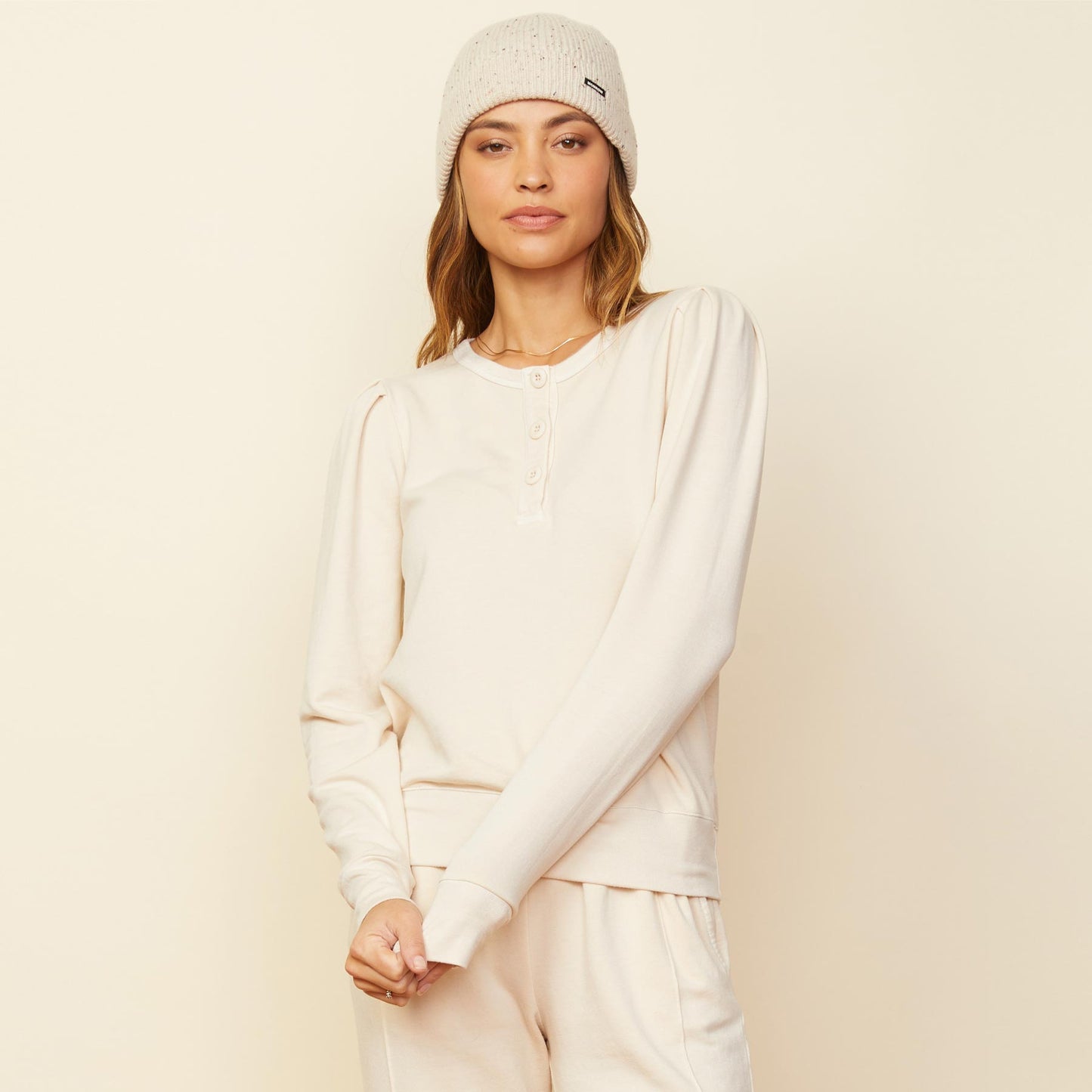Front view of model wearing the tucked sleeve henley in off white.