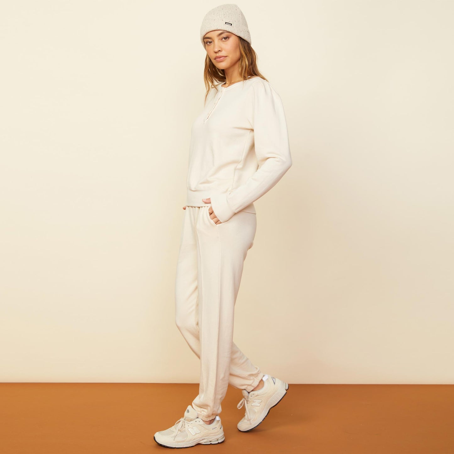 Side view of model wearing the tucked sleeve henley in off white.