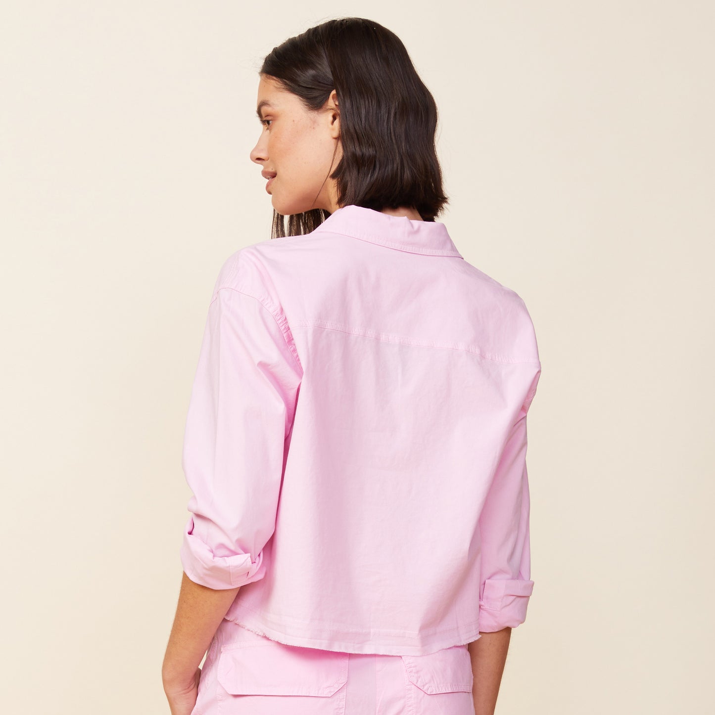 Back view of model wearing the cropped poplin shirt in pink lavender.