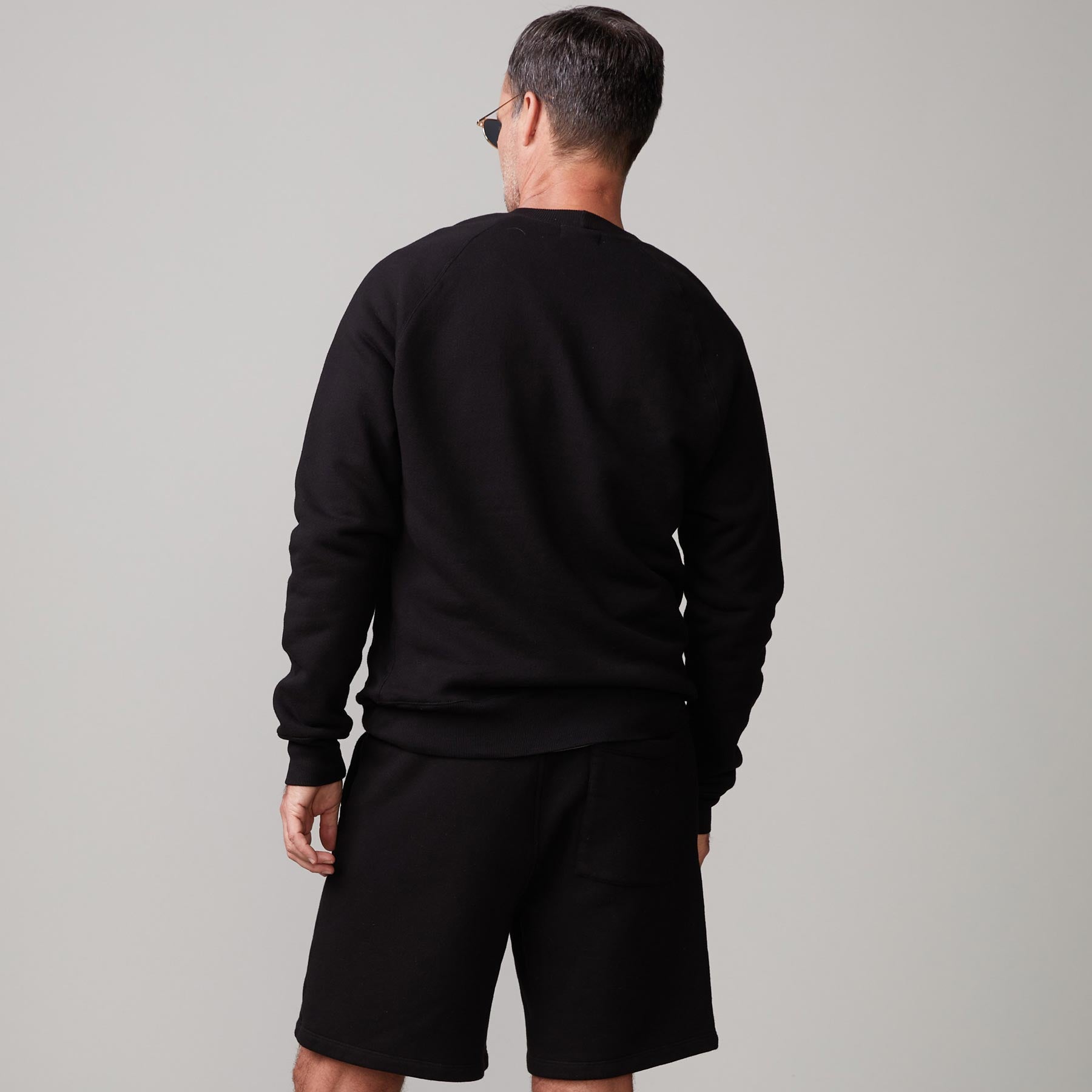 Back view of model wearing the 70's raglan in black.