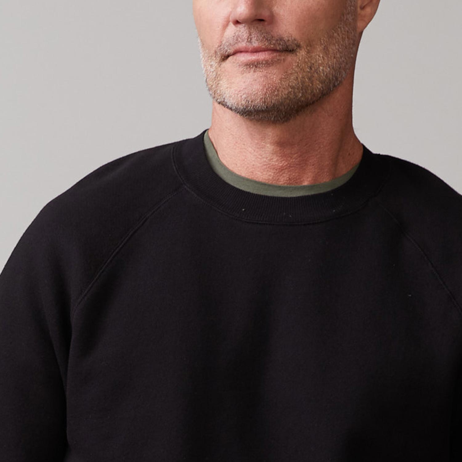 Close up view of model wearing the 70's raglan in black.