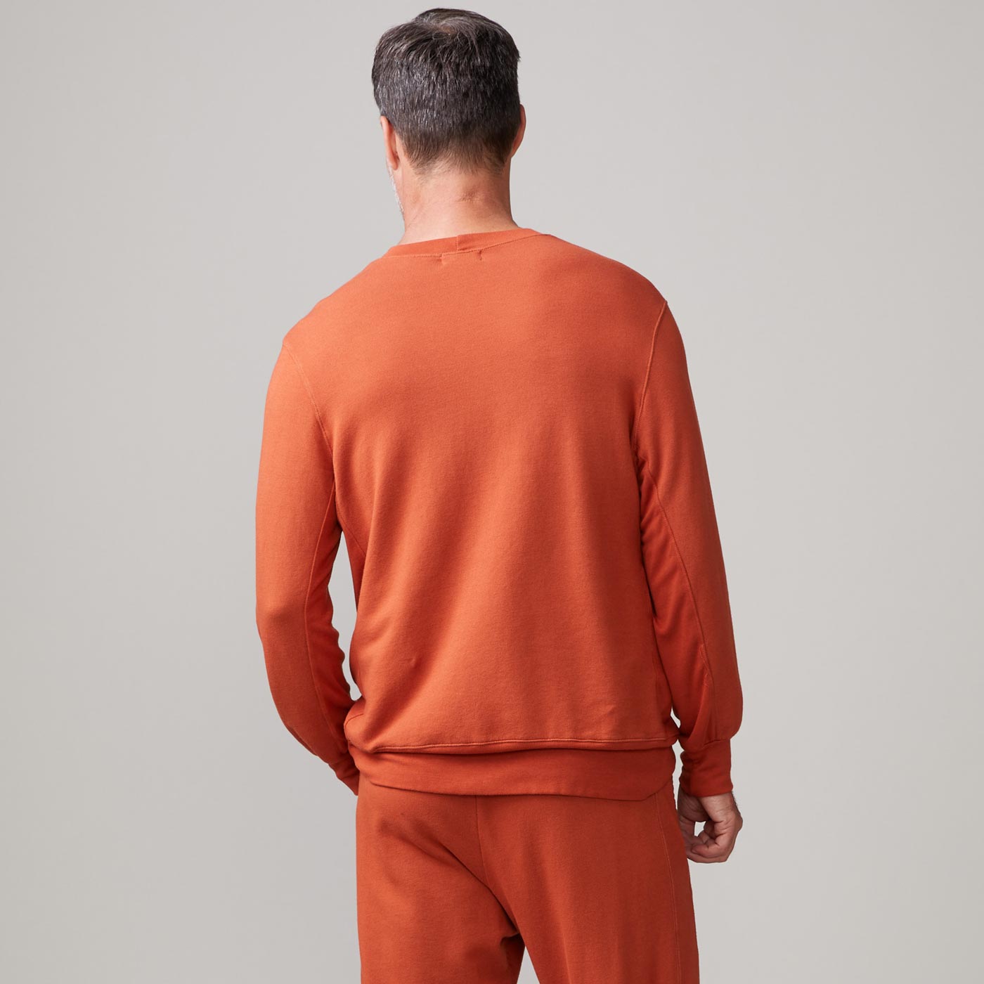 Back view of model wearing the lounge sweatshirt in faded rust.