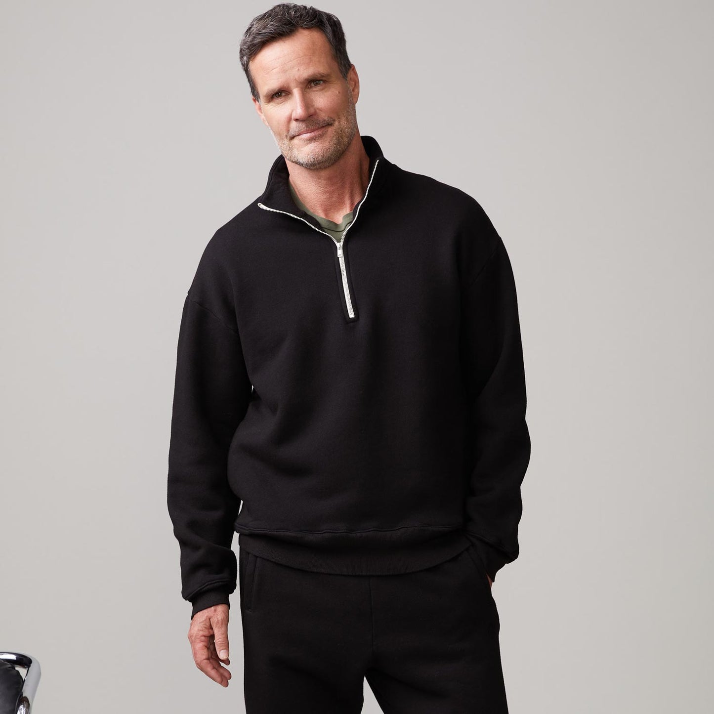 Front view of model wearing the half zip sweatshirt in black.