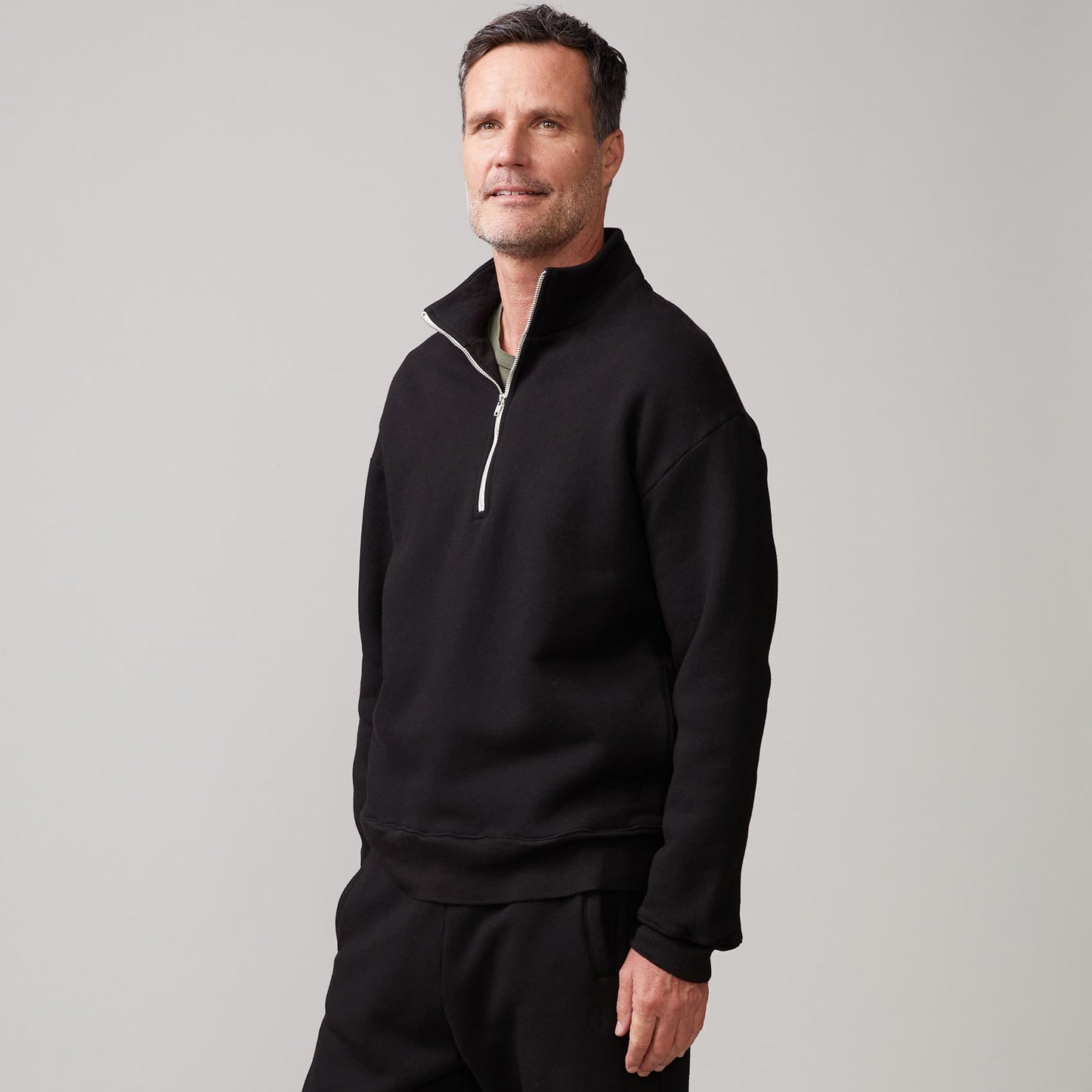 Side view of model wearing the half zip sweatshirt in black.