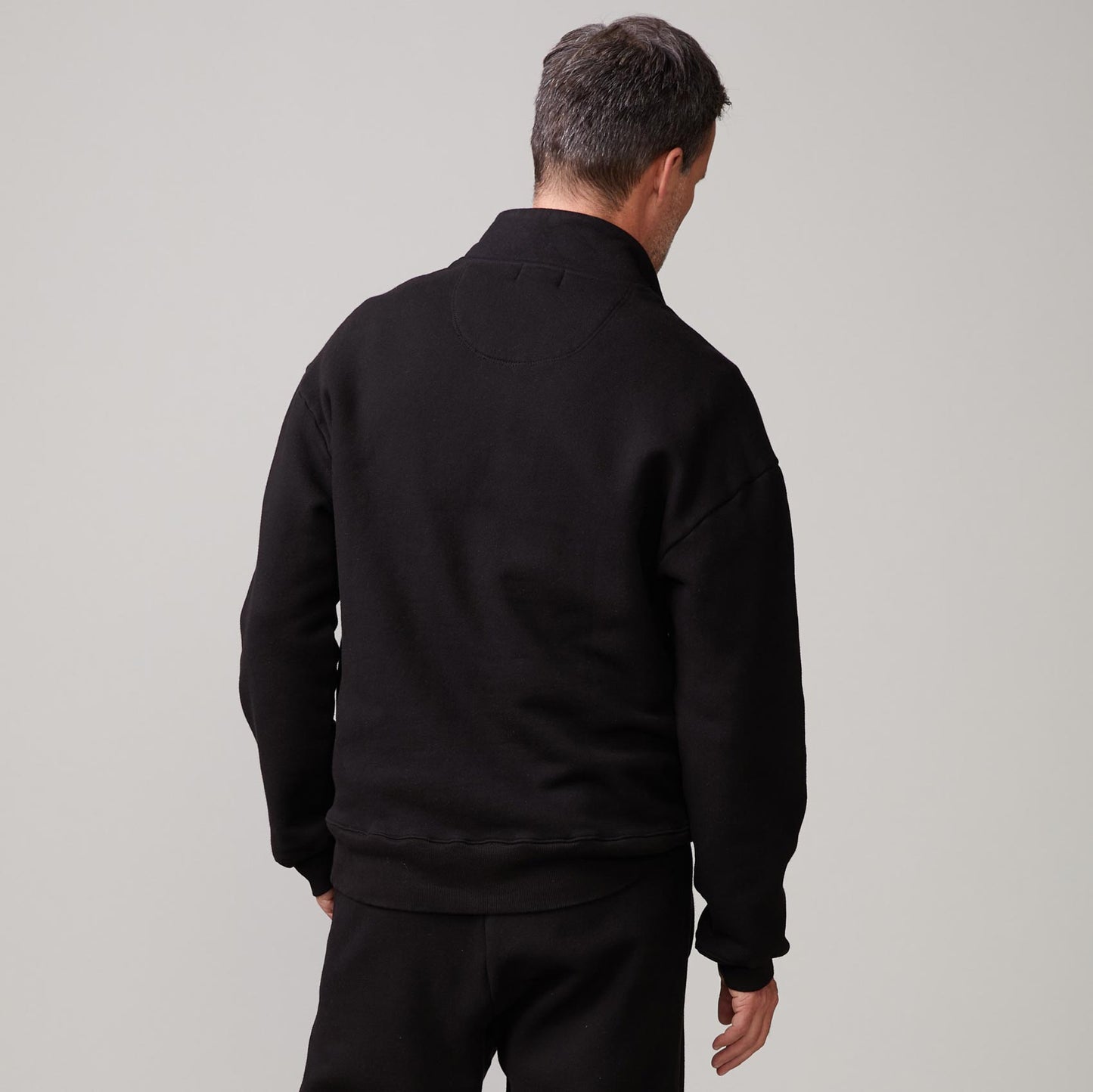 Back view of model wearing the half zip sweatshirt in black.