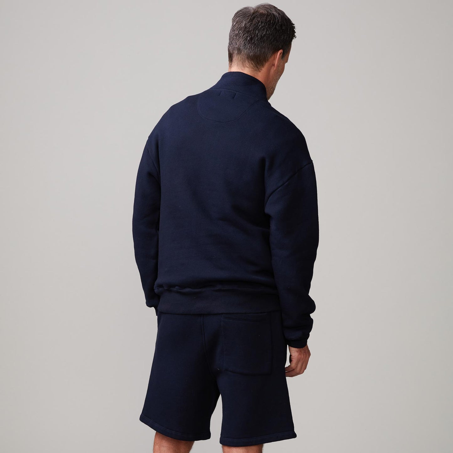 Back view of model wearing the half zip sweatshirt in indigo.