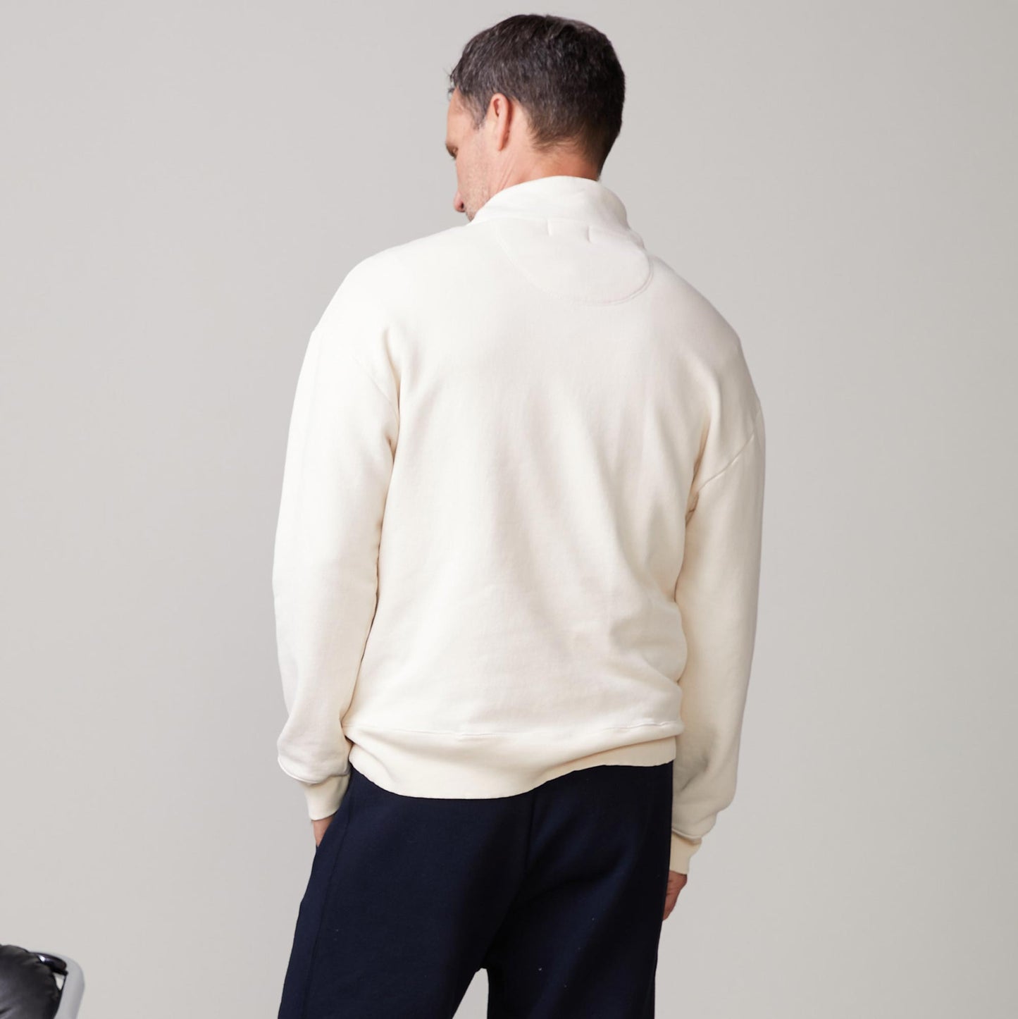Back view of model wearing the half zip sweatshirt in off white.