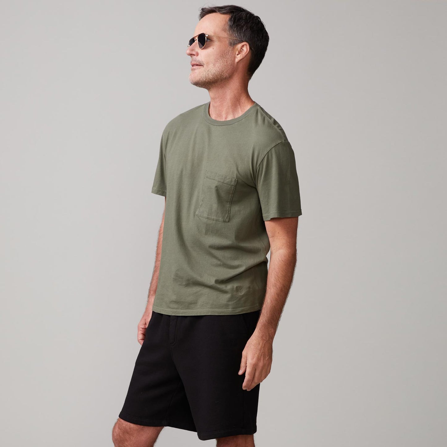 Side view of model wearing the relaxed pocket crew in general green.