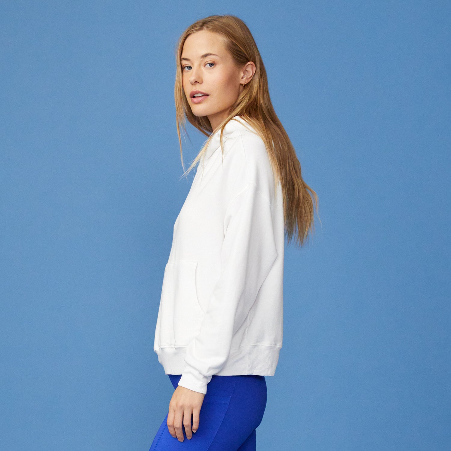 Side view of women in white supersoft fleece slouchy hoody paired with Electric Blue Biker shorts