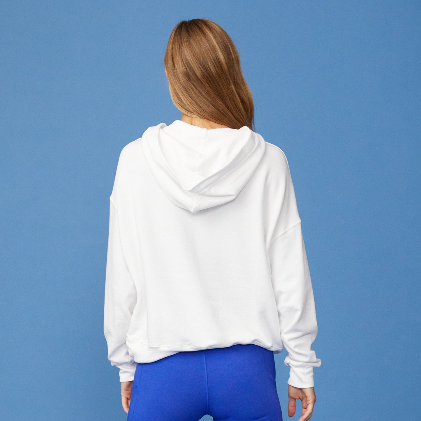 Rear view of women in white supersoft fleece slouchy hoody paired with Electric Blue Biker shorts